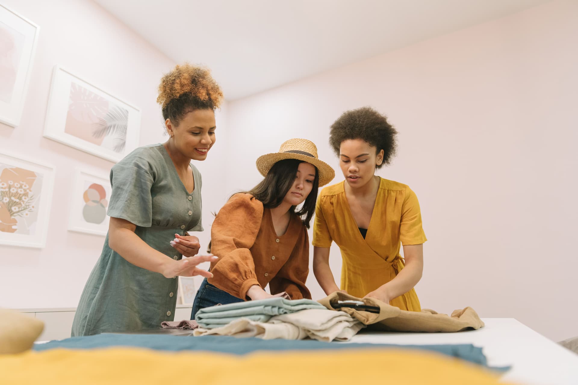 Tres mujeres trabajan juntas en una boutique y conversan sobre diseños de moda.